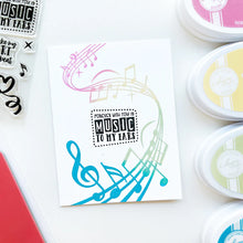 Load image into Gallery viewer, Catherine Pooler - Background Stamp - On Staff. Add some dancing notes to your card background with the On Staff Background Stamp. This red rubber stamp features a winding music staff pattern with notes and musical icons. Available at Embellish Away located in Bowmanville Ontario Canada. Card example by brand ambassador.