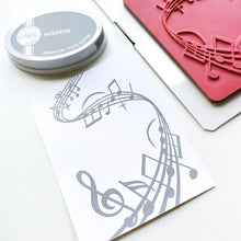 Load image into Gallery viewer, Catherine Pooler - Background Stamp - On Staff. Add some dancing notes to your card background with the On Staff Background Stamp. This red rubber stamp features a winding music staff pattern with notes and musical icons. Available at Embellish Away located in Bowmanville Ontario Canada.