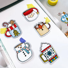 Load image into Gallery viewer, Catherine Pooler - Stamp & Die Set - Holiday Mug. From the makers of the original Mug Shots Stamp Set comes Holiday Mug Shots Stamps and coordinating dies! Features all your favorite winter friends- Santa, Rudolf, Snowman and even the Gingerbread man. Available at Embellish Away located in Bowmanville Ontario Canada.