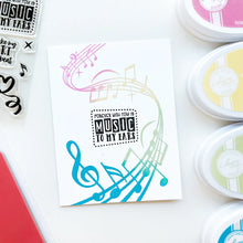 Load image into Gallery viewer, Catherine Pooler - Background Stamp - On Staff. Add some dancing notes to your card background with the On Staff Background Stamp. This red rubber stamp features a winding music staff pattern with notes and musical icons. Available at Embellish Away located in Bowmanville Ontario Canada. Card example by brand ambassador.

